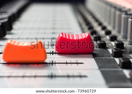 Orange and  red slider on a sound mixer with blurry background