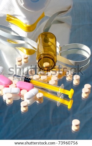 Medicine bottle and syringe and mask with pills and reflection