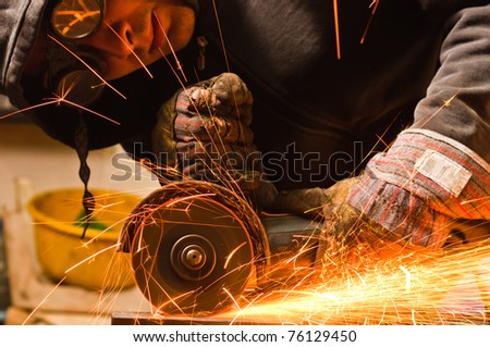 Worker cutting metal with many sharp sparks