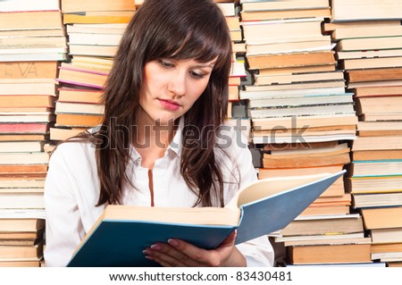 Beautiful young student girl reading from a big book