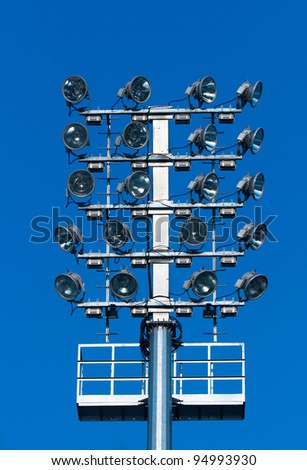 Stadium lighting with a lot of reflectors against blue sky
