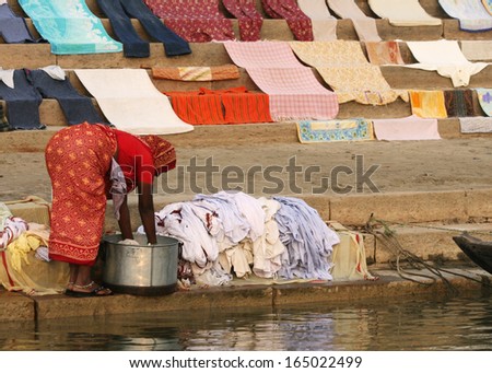 A woman washes clothes next to the Ganges River, in Varanasi, India.  Clothes seem to come out clean, although the river is extremely polluted.