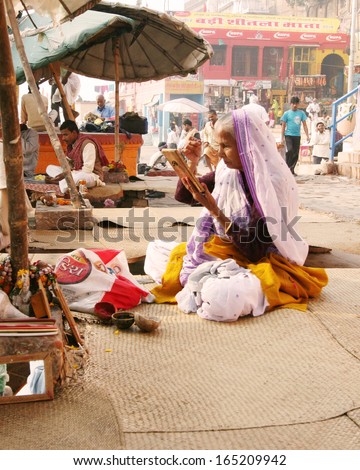 VARANASI, INDIA - NOVEMBER 28: An elderly woman uses a mirror to fix a bindi on her forehead on November 28, 2008 in Varanasi, India.