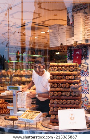 ISTANBUL, TURKEY - JULY 19, 2014: A young man arranges boxes of sweets in a Turkish bakery.