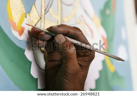 The hand of an Indian artist painting a Hindu God with a squirrel hair brush