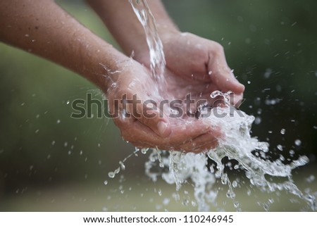 A pair of hands peacefully feel the refreshing water splashing into them.