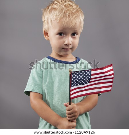 A young boy holds an American flag with a questioning look.