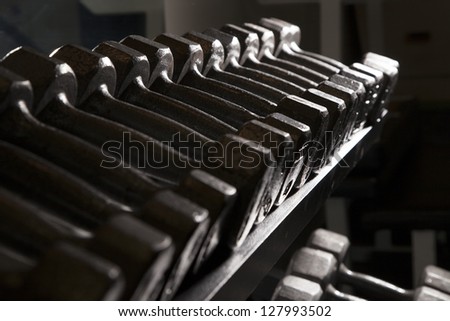 Free weights sitting on a weight rack. Dark intensity.