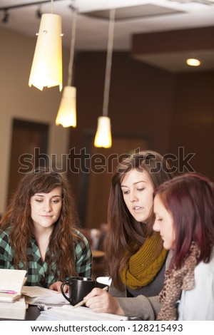 A group of beautiful young women talk around a table with bibles and notebooks.