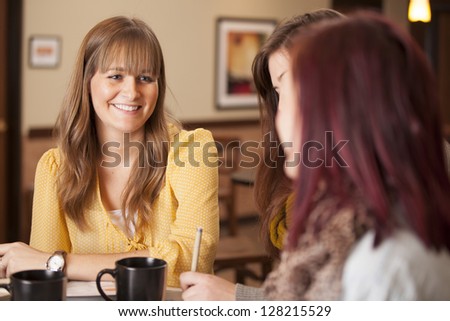 Three girls sit at a table with coffee and study Three girls sit at a table with coffee and study