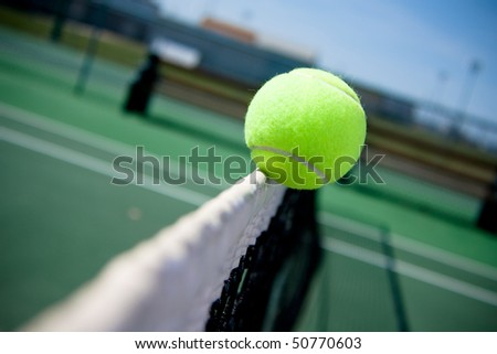 A tennis ball clips the top of the net and goes over to the other side.