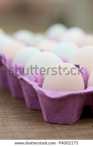 Macro of free range organic eggs in a purple crate.