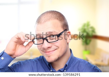 Young  attractive man  smiling in black eyeglasses in  office interior.