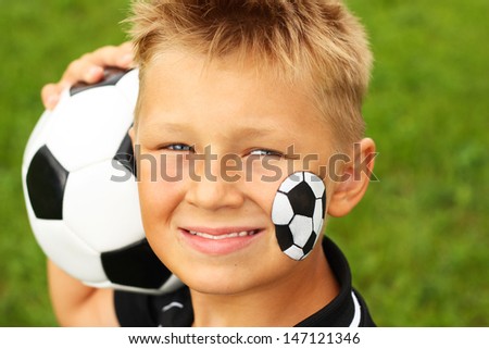 Young happy boy with painted face and soccer ball.
