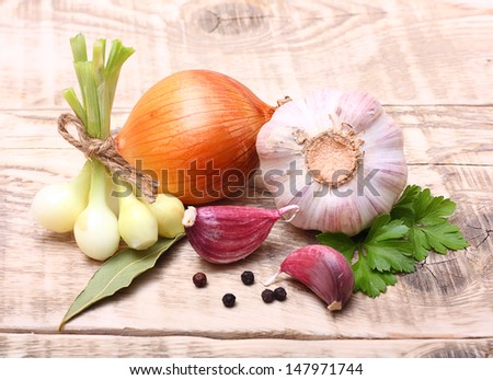 Garlic clove, onion and parsley leaves on wooden background