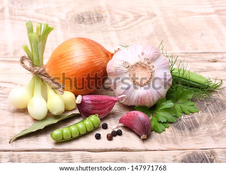 Garlic clove, onion and parsley leaves on wooden background