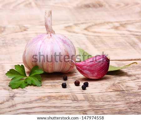 Garlic clove, pepper and parsley leaves on wooden background