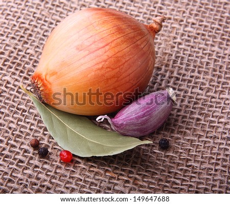 Garlic clove, onion and  laurel leaf on burlap background