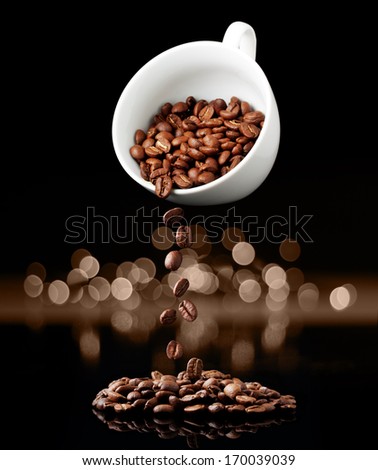 Coffee cup with falling grain against black wall.