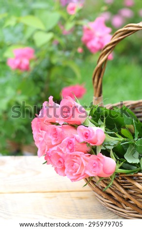 Pink roses in straw basket over garden background.