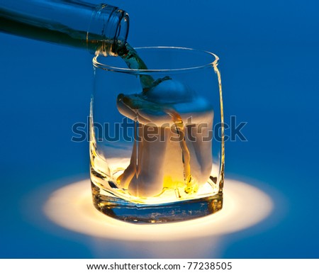 A glass with a woman figure inside and an alcoholic drink flowing in, blue background