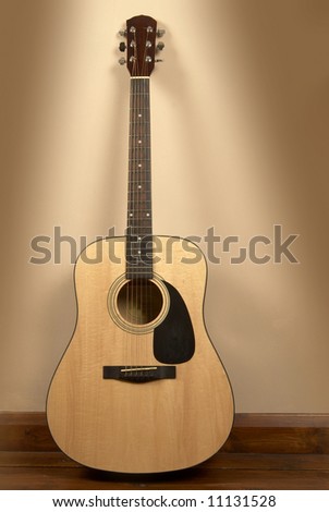 An old acoustic guitar leaning against interior wall