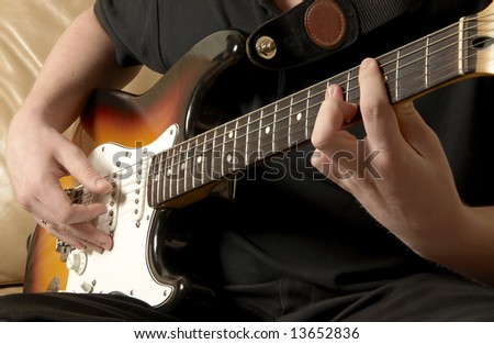Close up of a guitar player sat playing the electric guitar.