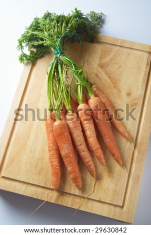 A bunch of organic carrots on a wooden chopping board