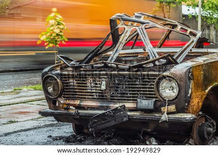 ODESSA - MAY 14: Front view of burned car on road with car traffic on a background on May 14, 2014 in Odessa, Ukraine. Abandoned car was exploded at night time on May 10, 2014. Long exposure shot.