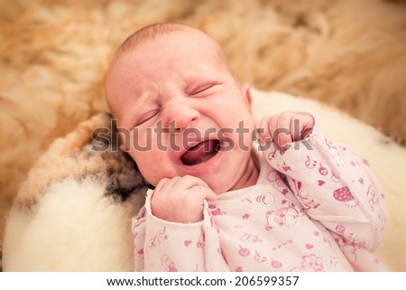 One month old baby crying in fury cover close up