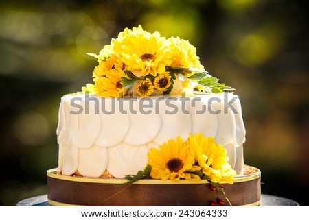 white creamy delicious cake decorated with yellow flowers and green leafs