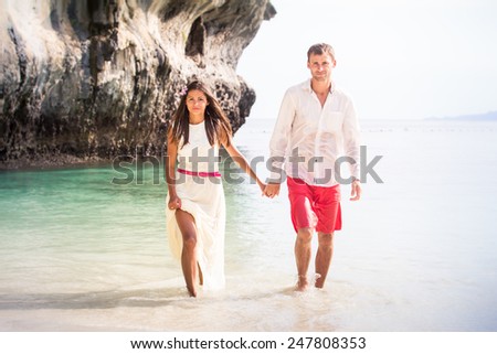 brunette girl with handsome man walk out the sea water in island bay with green mountain background
