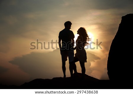silhouette of kissing guy and girl against sun at dawn