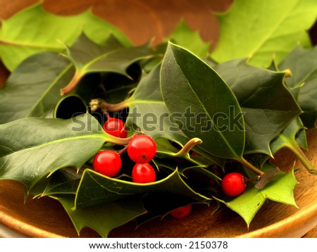 Red berries and holly leaves in a wooden bowl