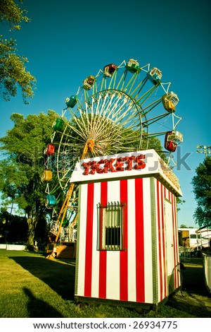 Ticket booth in front of a colorful carnival ferris wheel.