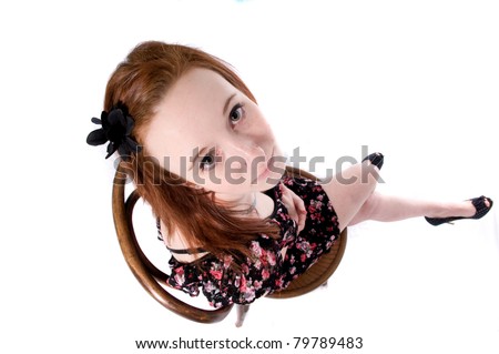Attractive young woman is skirt sits on chair looking up at camera in unusual angle