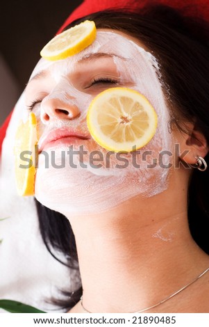 The woman in the cosmetic lounge with the mask and fruit on the face.