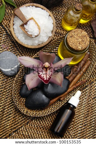 herbal salt in bowl and with orchid, stones and massage oil towel on burlap texture