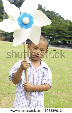 Little boy standing with playing with windmill toys windmill toys in the green rice fields