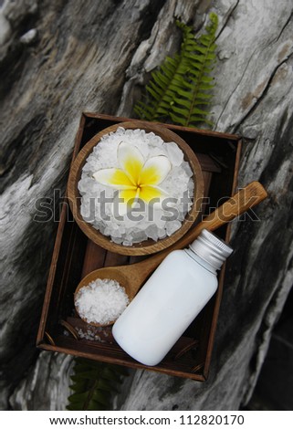 salt with frangipani in bowl spoon with bamboo grove with massage oil on driftwood