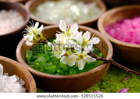 color sea salt in wooden bowl with cherry flower ,massage oil on green towel