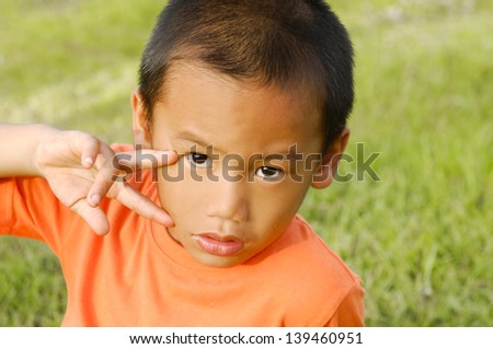 little boy showing victory hand sign on the green grass