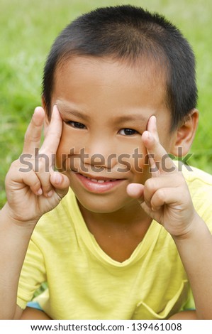 little boy showing victory hand sign on grass background