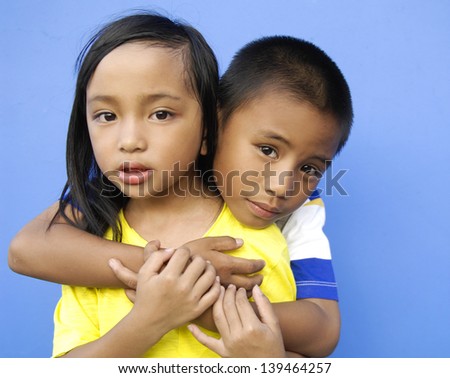 Sister Hugging Little Brother on blue background