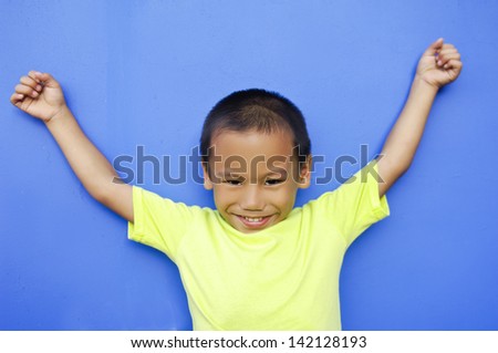 cute boy with shirt gesturing with his arms on blue background