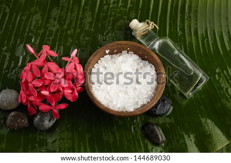 Pile of stones with branch tropical flower, salt in bowl ,massage oil on banana leaf
