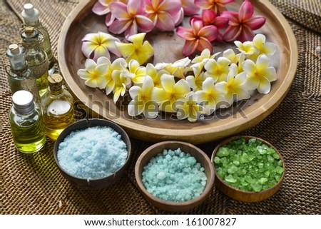 color sea salt in wooden bowl with red and white perfume ,massage oil on mat