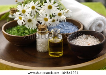 color sea salt in wooden bowl with and salt in glass, massage oil ,towel on bowl