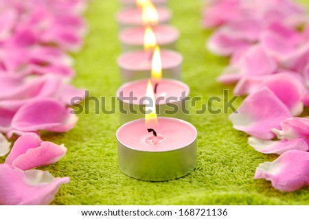 Set of candles with rose petals and green towel