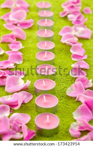 Pink rose petals and candles green towel